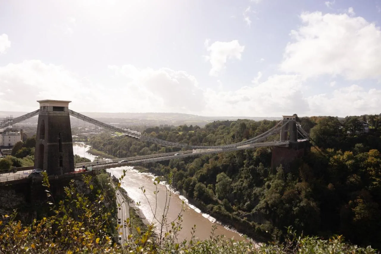 a suspension bridge over a river with trees at Moxy Bristol in Bristol